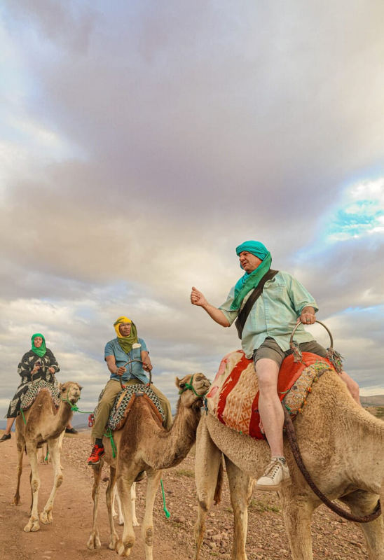 agafay desert sunset Tourists riding camels across the Agafay Desert landscape near Marrakech Morocco