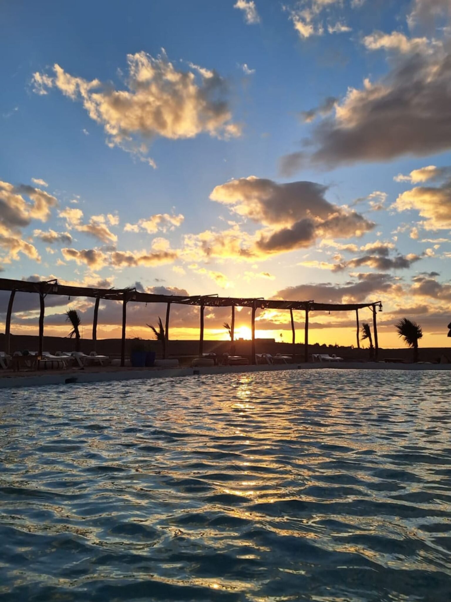 Client enjoying breathtaking sunset over Agafay Desert at Agafay Oasis Sky in Marrakech, with golden skies and desert views.
