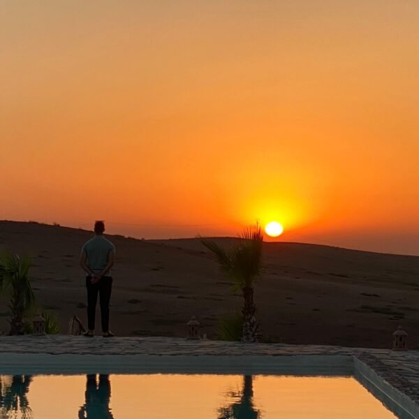 Client enjoying breathtaking sunset over Agafay Desert at Agafay Oasis Sky in Marrakech, with golden skies and desert views.