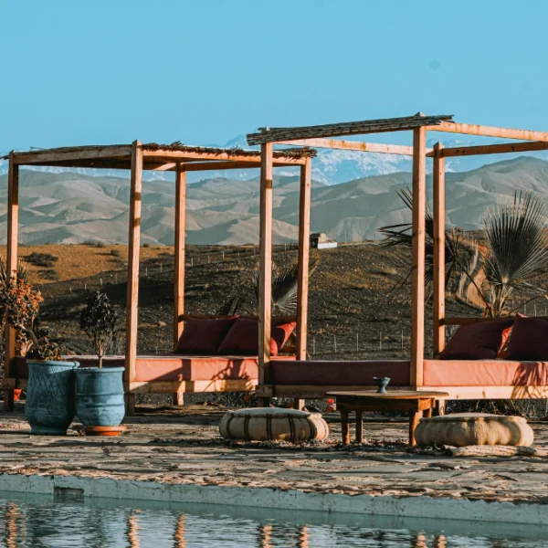 Agafay desert Marrakech luxury camp poolside lounge with Atlas Mountains view, relaxing seating area in agafay desert near Marrakech