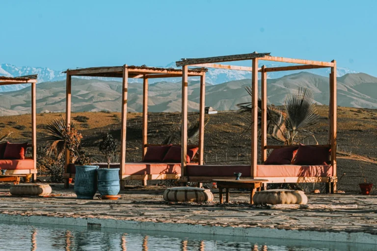 Agafay desert Marrakech luxury camp poolside lounge with Atlas Mountains view, relaxing seating area in agafay desert near Marrakech