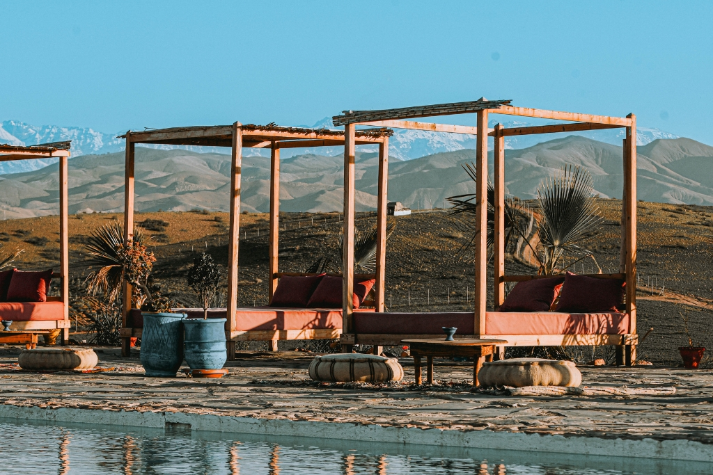 Agafay desert Marrakech luxury camp poolside lounge with Atlas Mountains view, relaxing seating area in agafay desert near Marrakech